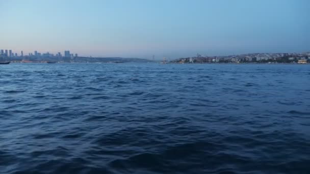 Vagues de mer bleu profond contre la ville au crépuscule vue du navire — Video