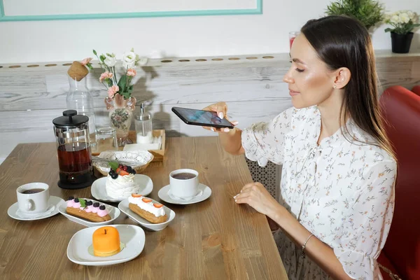 Uśmiechnięta dziewczyna bierze obraz ciasta i herbaty w tabeli w kawiarni — Zdjęcie stockowe