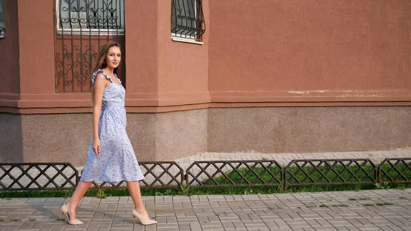 Стройная европейская модель в модном голубом платье прогуливается по улице — стоковое фото