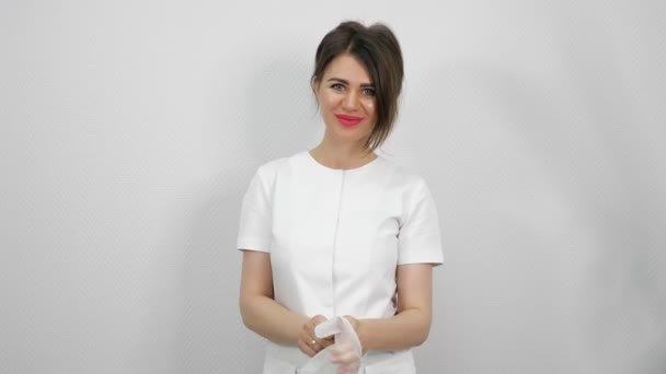 Красивый косметолог надевает резиновую перчатку на руку крупным планом — стоковое видео
