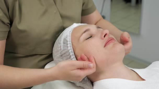 Косметолог делает профессиональный массаж лица вид сбоку — стоковое видео