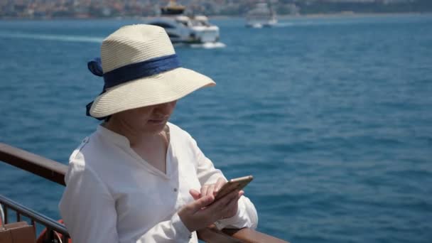 Žena stojí na palubě lodi a surfuje na internetu proti jachty — Stock video