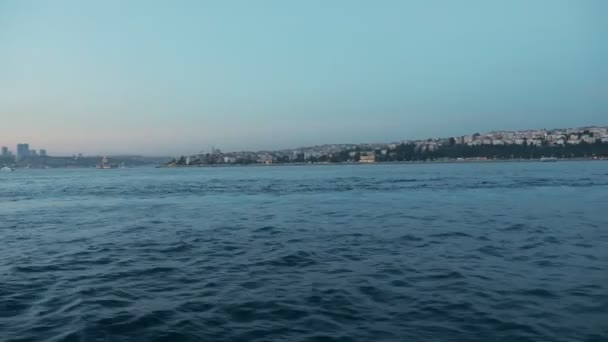 Olas de mar azul profundo contra la ciudad en vista del atardecer desde el barco — Vídeos de Stock