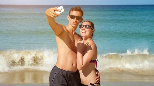 Familia sonriente hace selfie en la playa soleada cerca del océano azul — Foto de Stock