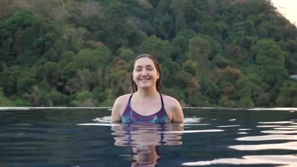 Senhora sorridente em abordagens maiô coloridas na piscina azul — Vídeo de Stock