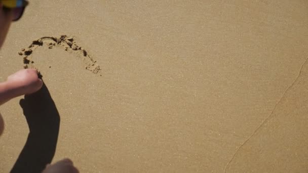 A mulher desenha um coração na areia molhada. Movimento lento — Vídeo de Stock