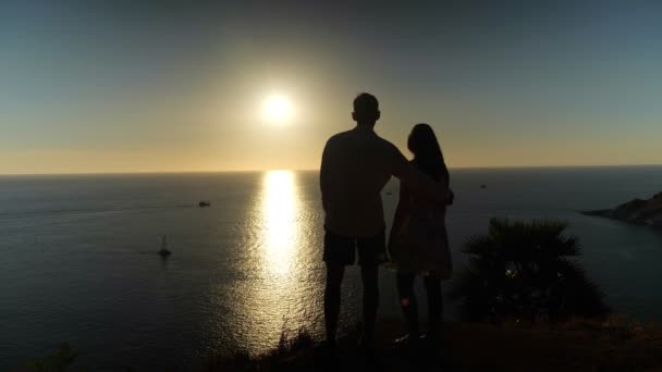 Romantikus pár ölelések álló óceán partján szélén naplementekor — Stock videók