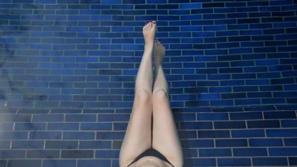 Donna oscilla gambe nude con manicure rossa in acqua della piscina — Video Stock