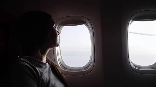 Kobieta w szarym t-shircie sylwetka przed samolotem jasne okna — Zdjęcie stockowe
