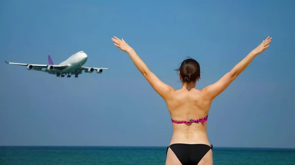 女性は海のそばに立って飛行機の上を飛んで ストック画像