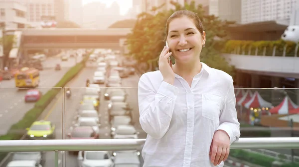 Fiatal nő beszél fehér okostelefon és vidáman mosolyog — Stock Fotó