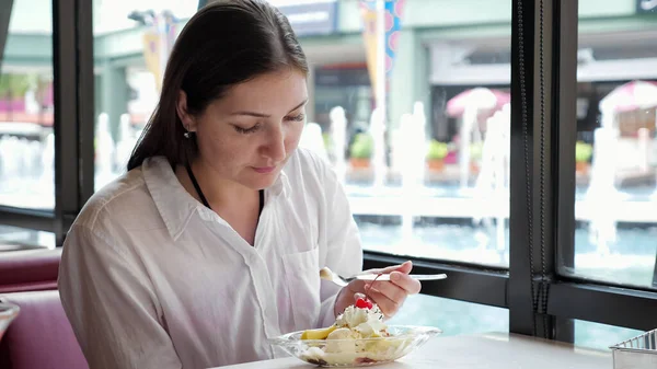 穿着白衬衫的布鲁内特在咖啡馆的桌子边吃冰淇淋 — 图库照片