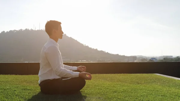 Ragazzo medita sotto la luce del sole contro collina verde sulla terrazza — Foto Stock