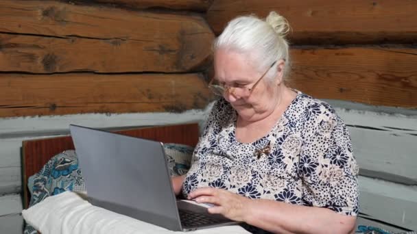 Mujer de pelo blanco en gafas escribiendo en un ordenador portátil — Vídeos de Stock