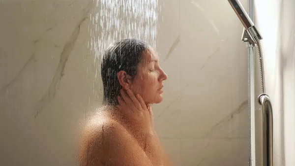 Attraktive brunette står under tungt vandtryk - Stock-foto