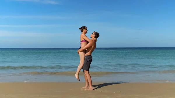 Радостные молодые пары обнимаются на солнечном пляже возле океана — стоковое фото