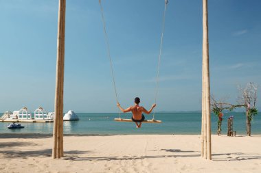 Kadınlar okyanus kıyısındaki egzotik tatil beldesinde salıncakta sallanıyor