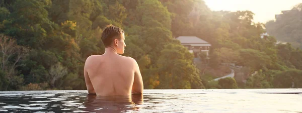 Homme à l'hôtel piscine extérieure regardant la forêt tropicale pittoresque paysage vallonné — Photo