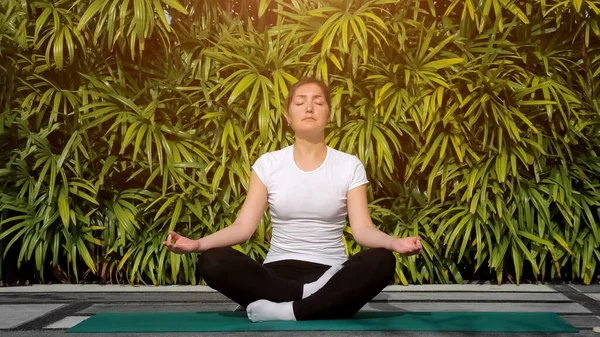 Meditazione all'aria aperta. Donna in t-shirt bianca in posizione loto — Foto Stock