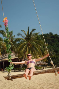 Bikinili bir kadın sahilde sallanıyor.