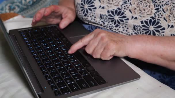 Egy idős nő gépel egy laptopon. Kéz és billentyűzet közelsége — Stock videók