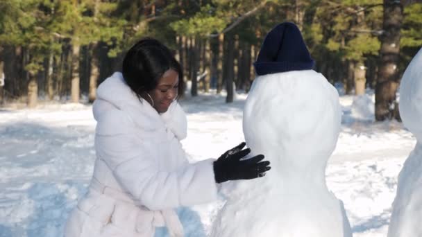 Menina afro-americana faz boneco de neve entre a natureza de inverno — Vídeo de Stock