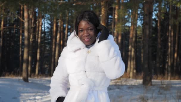 Negro chica poses cogidas de la mano en bolsillos contra snowy park — Vídeos de Stock