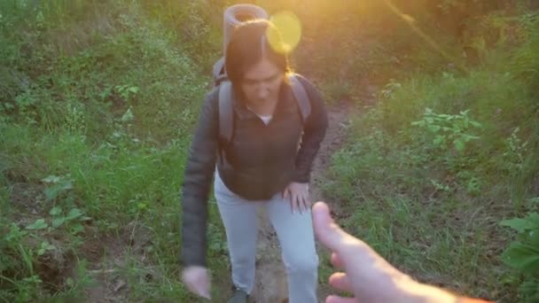 Manlig hand hjälper en kvinna med ryggsäck att resa sig från en ravin i skogen. Långsamma rörelser — Stockvideo