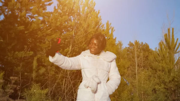 Schwarze Frau macht Selfie im Winterwald bei klarem Himmel — Stockfoto