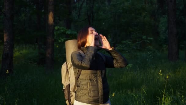 Een jonge vrouw met een rugzak is verdwaald in het bos. Schreeuwt om hulp — Stockvideo