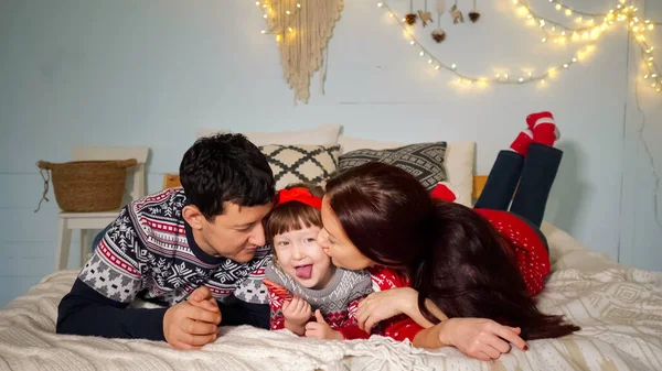Genitori sdraiati sul letto e baciare figlia posa a photoshoot — Foto Stock
