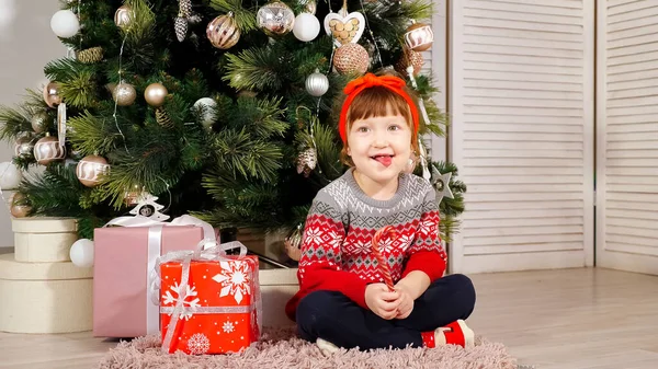 Niña se sienta bajo el árbol de Navidad riendo — Foto de Stock