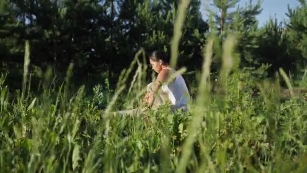 Woman yogi on a gym mat. Camera movement among grass — Stock Video