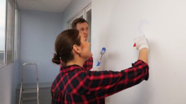 Kadın duvarlara kalp çiziyor. Kocasıyla birlikte evi onarıyor.