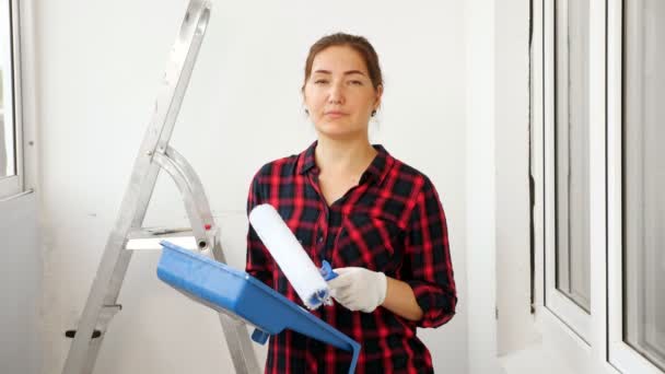 Vrouw in rood shirt houdt container en roller op terras — Stockvideo