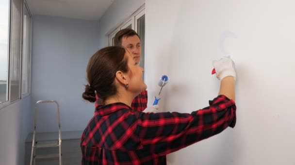 女人和丈夫一起在墙上打起精神来修理房子 — 图库视频影像