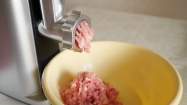 Elektrikli öğütücü kullanarak evde kıyma yapmak. Masada kıymalı plastik kase.