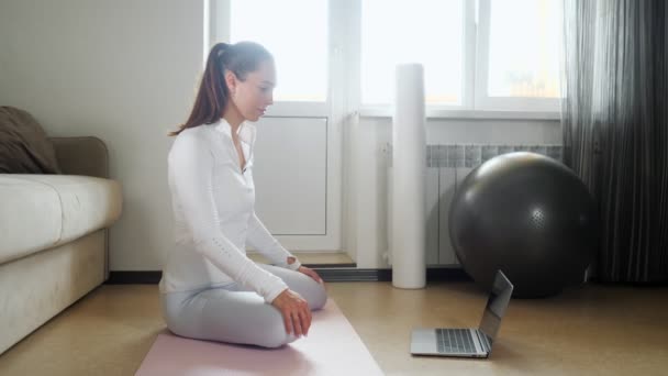 Fille regarde vidéo de la formation sur ordinateur portable assis sur le sol — Video