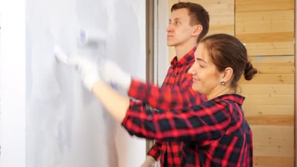 Жінка з пензлем і чоловік з валиком фарбують стіну на терасі — стокове відео