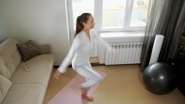 Активна жінка стрибає з піднятим тренуванням коліна вдома — стокове відео