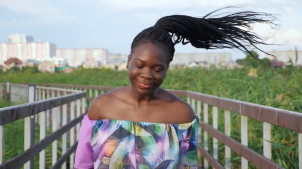 Afro-américaine dame en chemisier secoue les cheveux longs sur le pont — Video