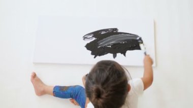 Aktif küçük kız siyah boyalı kağıt üzerine çizim yapıyor.