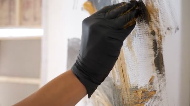 Main féminine dessine la peinture dans des gants debout dans l'atelier avec des murs blancs — Video