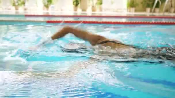 Wysportowana kobieta w czapce i goglach pływa z przodu czołgać się w basenie — Wideo stockowe