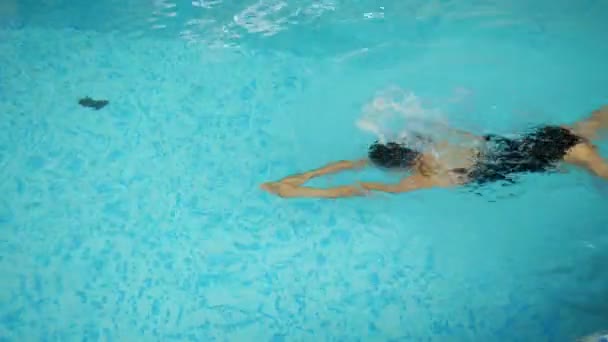 Ung kvinna i mössa och glasögon simmar i poolen — Stockvideo