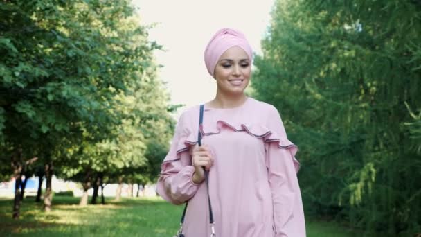 긴 자주색 드레스를 입고 공원을 따라 방랑하는 히잡 — 비디오