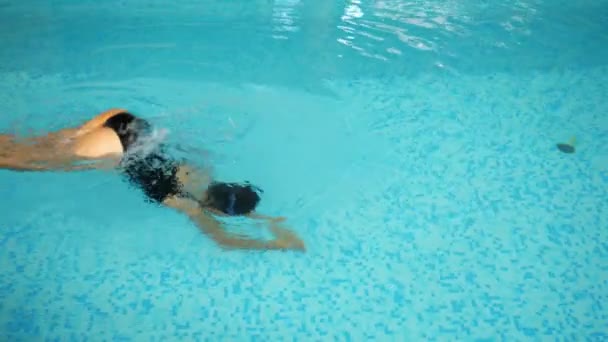 Kvinne dykker og svømmer brystsvømmende i basseng rent vann – stockvideo