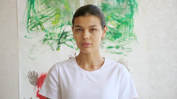 Concentrated artist in t-shirt smiles against masterpiece — Stock Video