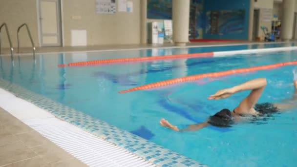 앞으로 수영하는 여자가 수영장 가장자리로 기어가서는 고글을 벗는다 — 비디오