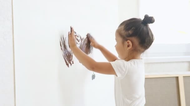Enfant en t-shirt blanc dessine sur toile blanche avec peinture marron — Video
